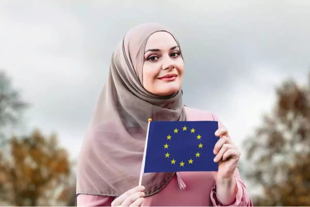 Woman wearing a hijab holding a European Union flag in an outdoor setting