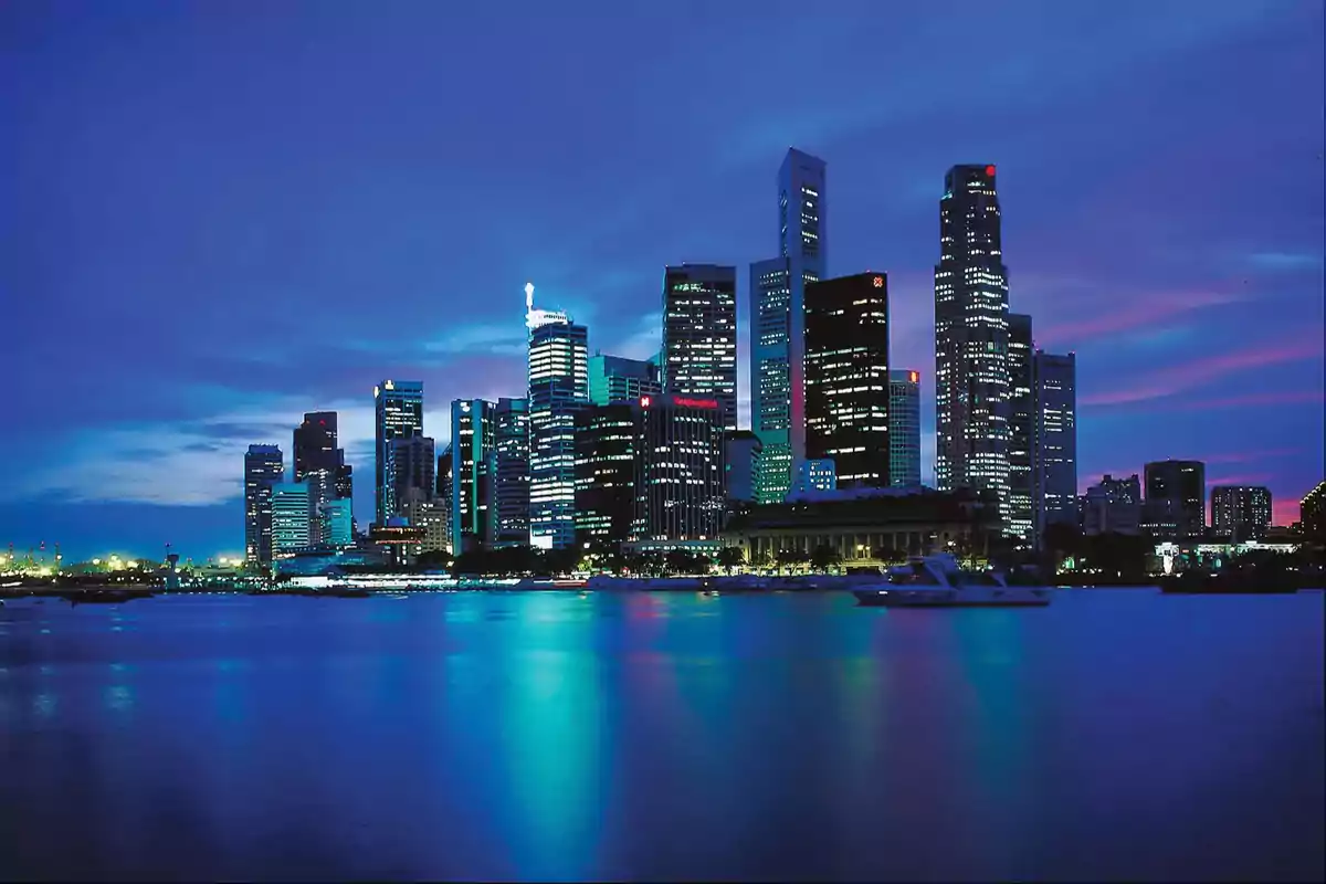 A modern city with skyscrapers lit up at dusk reflecting on the water. A modern city with skyscrapers lit up at dusk reflecting on the water.