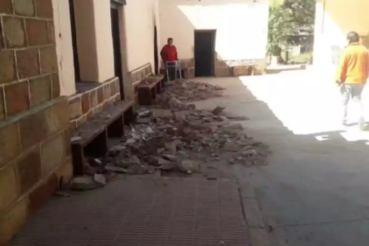 A hallway with debris on the floor and two people in the background. A hallway with debris on the floor and two people in the background.