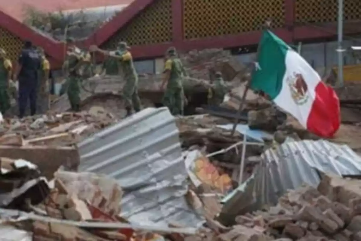 Soldiers working among rubble with a Mexican flag waving.