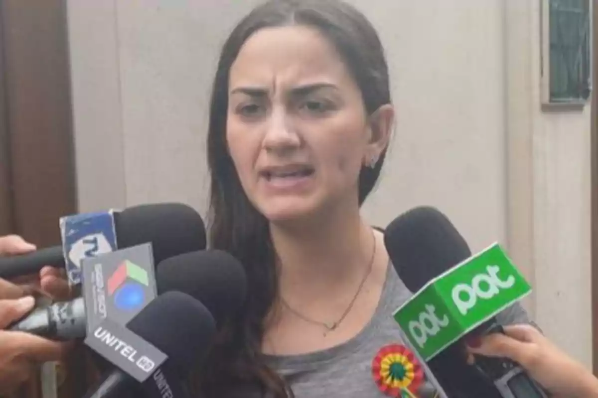 Una mujer hablando frente a varios micrófonos de diferentes medios de comunicación. Una mujer hablando frente a varios micrófonos de diferentes medios de comunicación.
