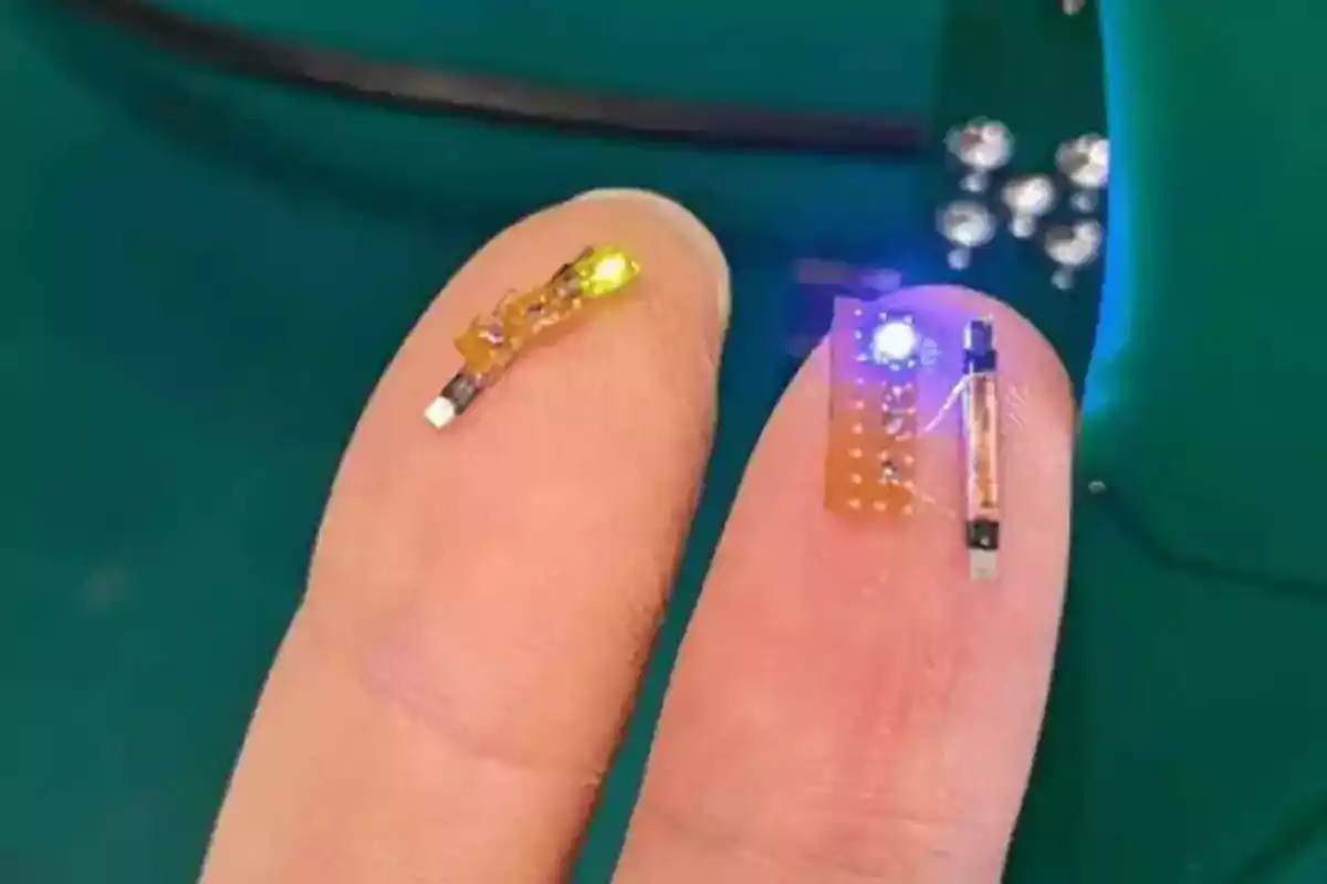Two fingers hold small electronic circuits with lit LED lights, one yellow and one blue, against a blurred green background. Two fingers hold small electronic circuits with lit LED lights, one yellow and one blue, against a blurred green background.