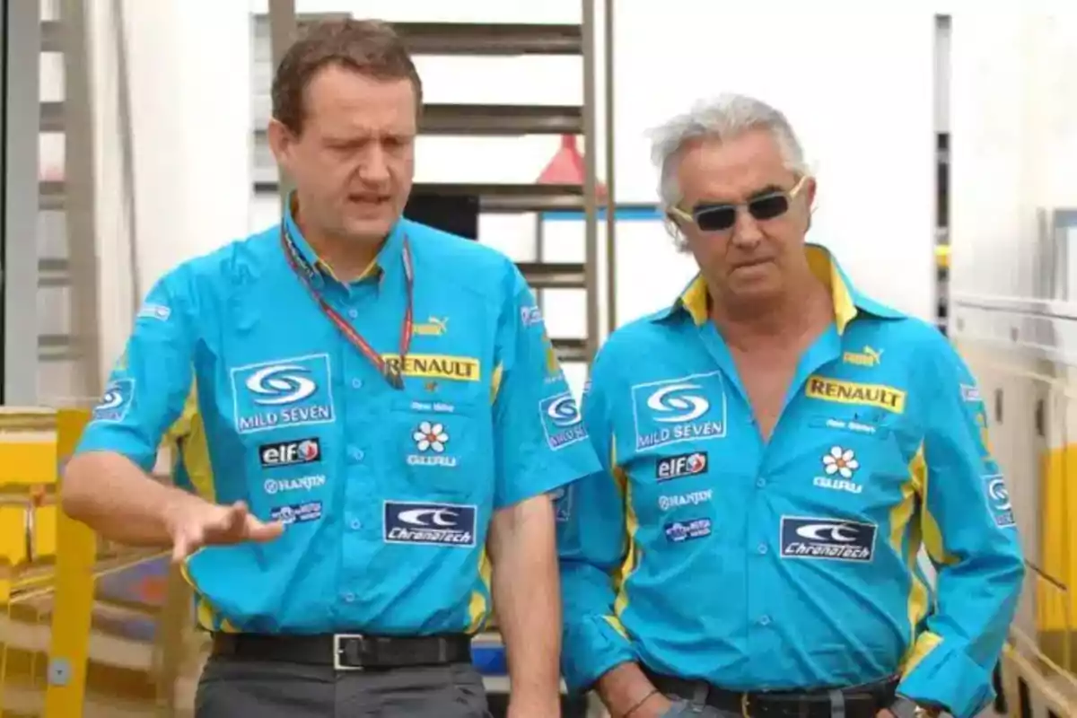 Two men wearing blue Renault Formula 1 team jerseys walk together in the paddock. Two men wearing blue Renault Formula 1 team jerseys walk together in the paddock.