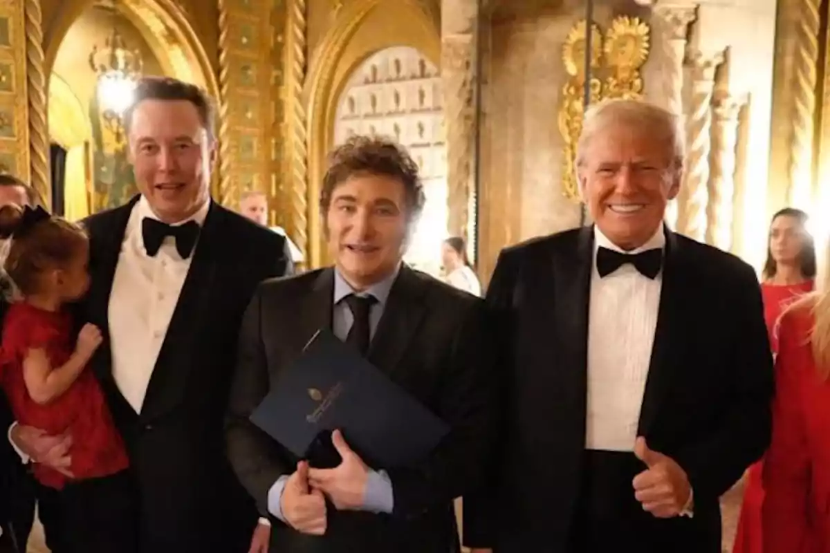 Un grupo de personas vestidas de gala posando en un elegante salón decorado con detalles dorados.