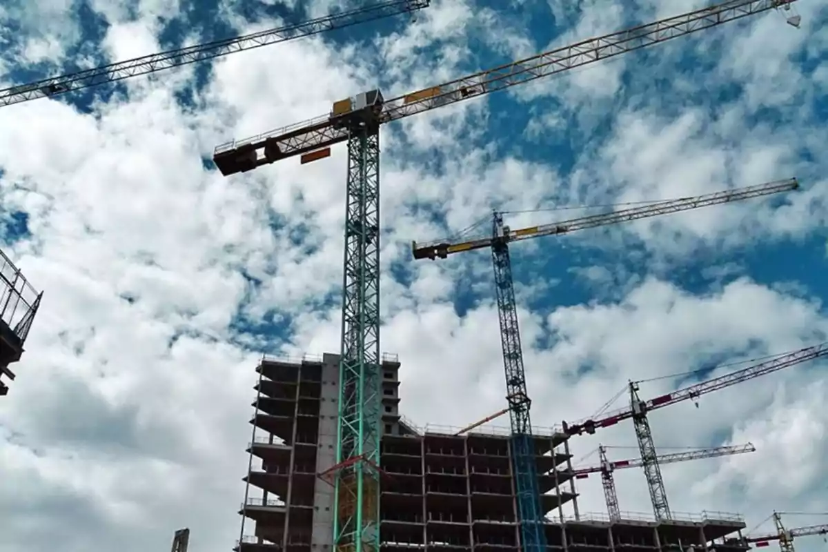 Varios edificios en construcción con grúas torre bajo un cielo parcialmente nublado