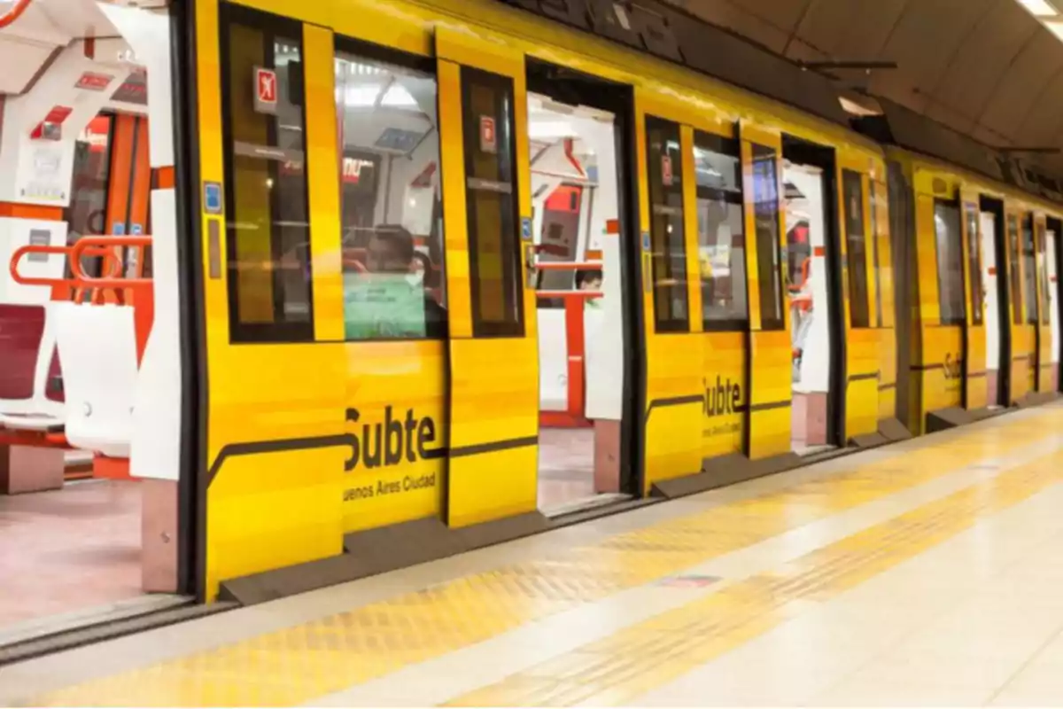 Un tren amarillo del subte de Buenos Aires con las puertas abiertas en una estación.