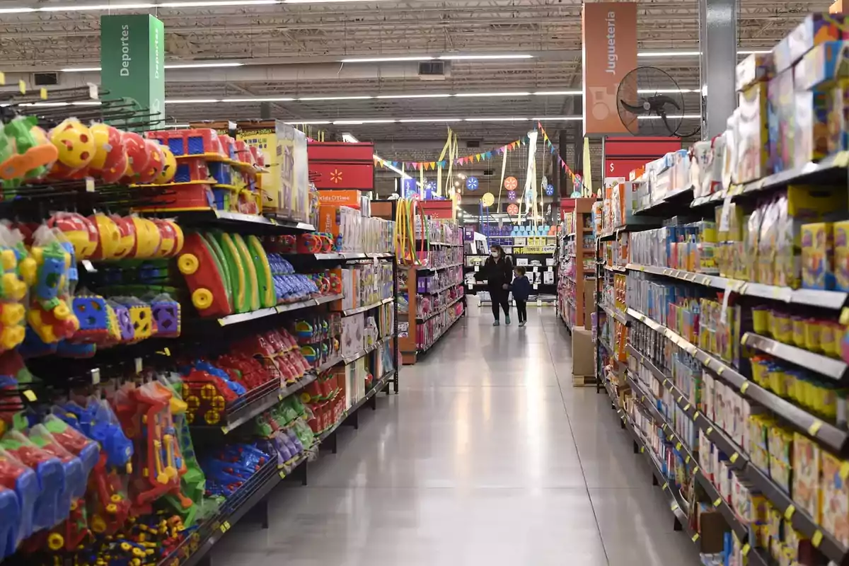 Pasillo de una tienda con estantes llenos de juguetes coloridos y una persona caminando con un niño. Pasillo de una tienda con estantes llenos de juguetes coloridos y una persona caminando con un niño.