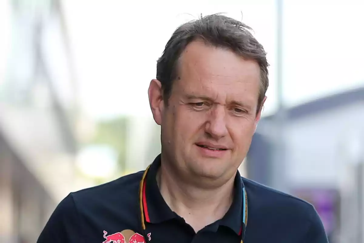 Short brown-haired man wearing a navy blue T-jersey with the Red Bull logo in a blurred outdoor setting. Short brown-haired man wearing a navy blue T-jersey with the Red Bull logo in a blurred outdoor setting.