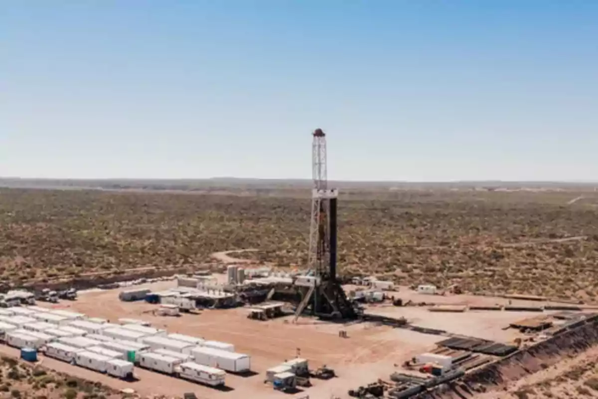 Plataforma petrolera en medio de un terreno árido con varios módulos y vehículos alrededor bajo un cielo despejado Plataforma petrolera en medio de un terreno árido con varios módulos y vehículos alrededor bajo un cielo despejado