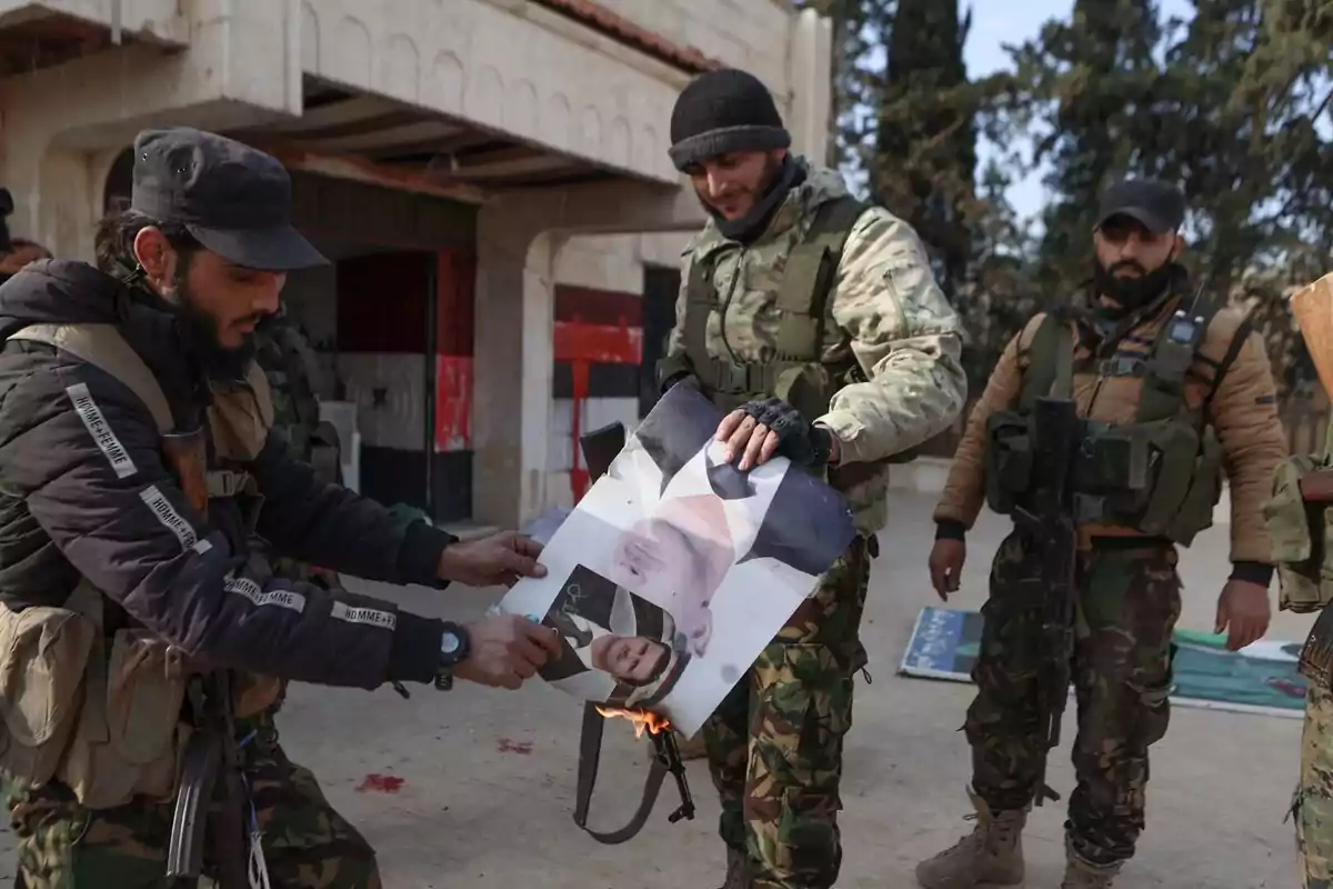 Un grupo de hombres con ropa militar quema un cartel en un entorno al aire libre.