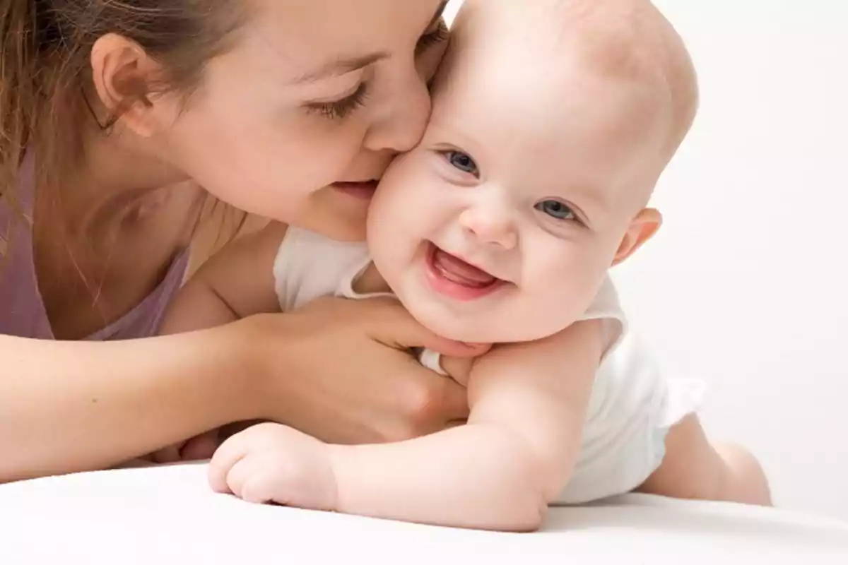 A young woman lovingly kisses a smiling baby. A young woman lovingly kisses a smiling baby.
