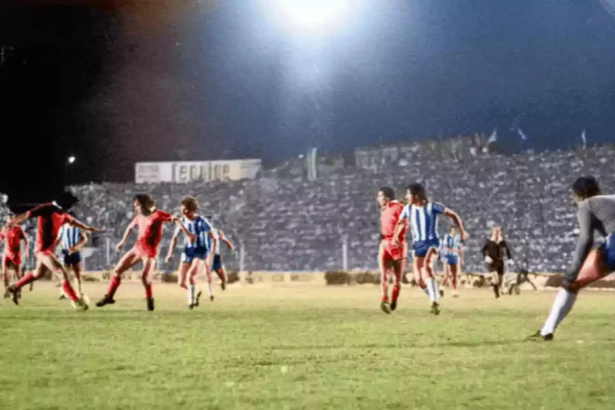 Soccer players in action during a night game in a stadium full of spectators. Soccer players in action during a night game in a stadium full of spectators.