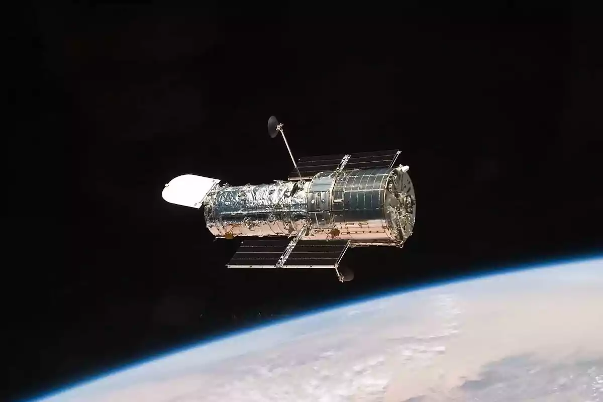 A space telescope floats in space with the Earth visible in the background. A space telescope floats in space with the Earth visible in the background.