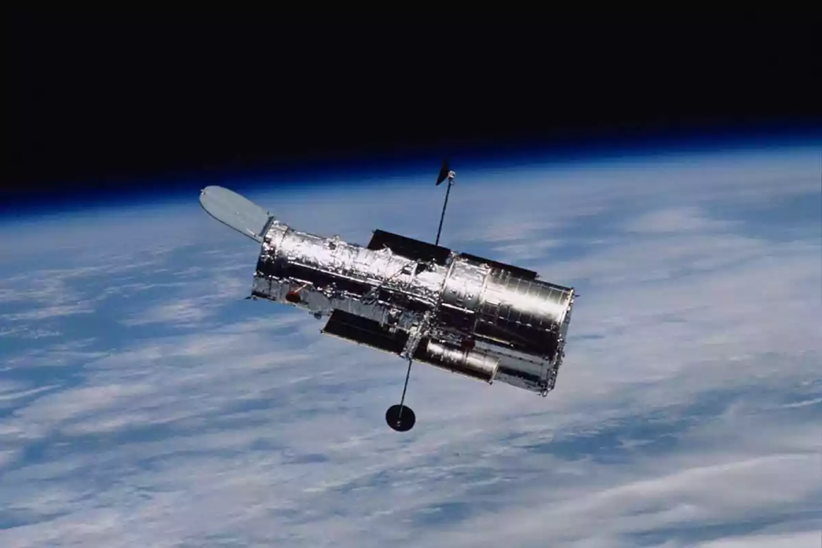 A space telescope floating in orbit above the Earth with the dark space in the background. A space telescope floating in orbit above the Earth with the dark space in the background.