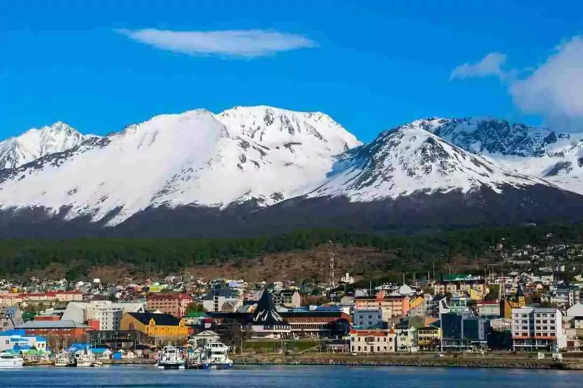 Una ciudad costera con montañas nevadas al fondo bajo un cielo azul brillante. Una ciudad costera con montañas nevadas al fondo bajo un cielo azul brillante.