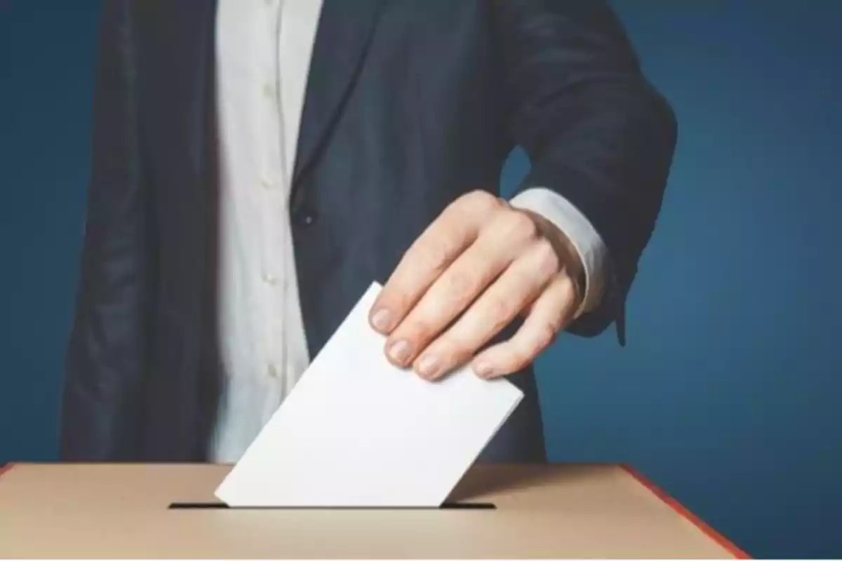 Persona depositando un sobre en una urna de votación. Persona depositando un sobre en una urna de votación.