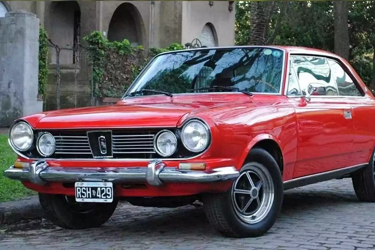 A red classic car parked on a cobblestone street in front of an old building. A red classic car parked on a cobblestone street in front of an old building.