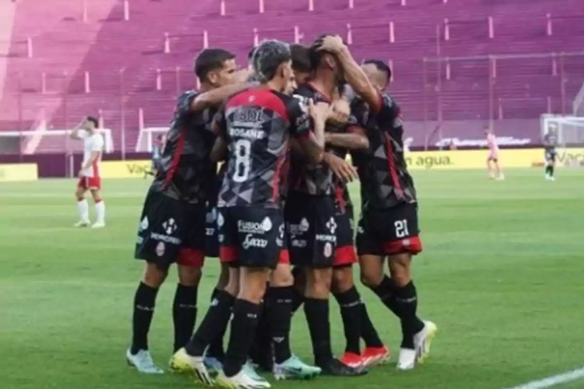 Jugadores de fútbol celebrando un gol en un estadio con gradas vacías. Jugadores de fútbol celebrando un gol en un estadio con gradas vacías.
