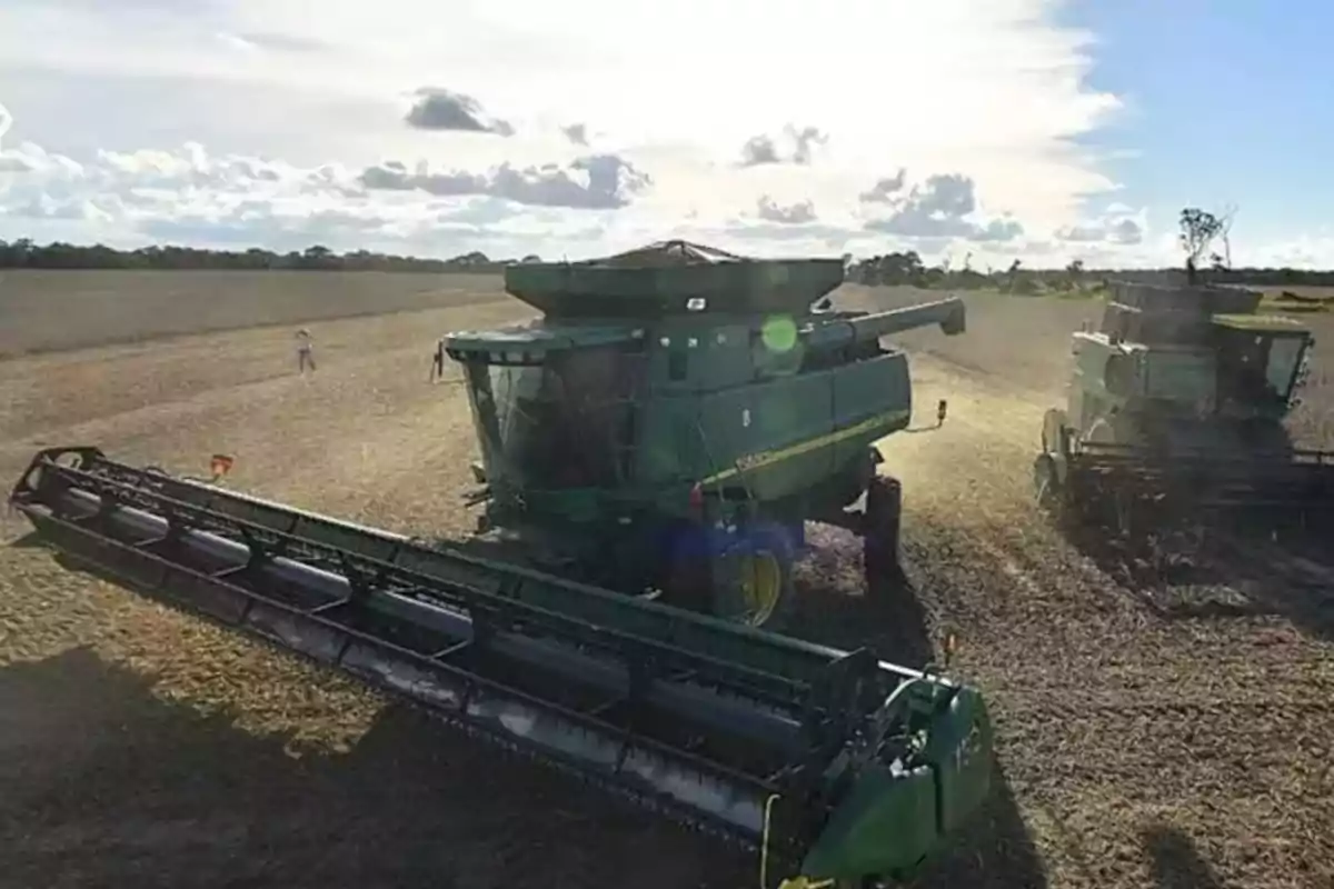 Cosechadora trabajando en un campo bajo un cielo parcialmente nublado.