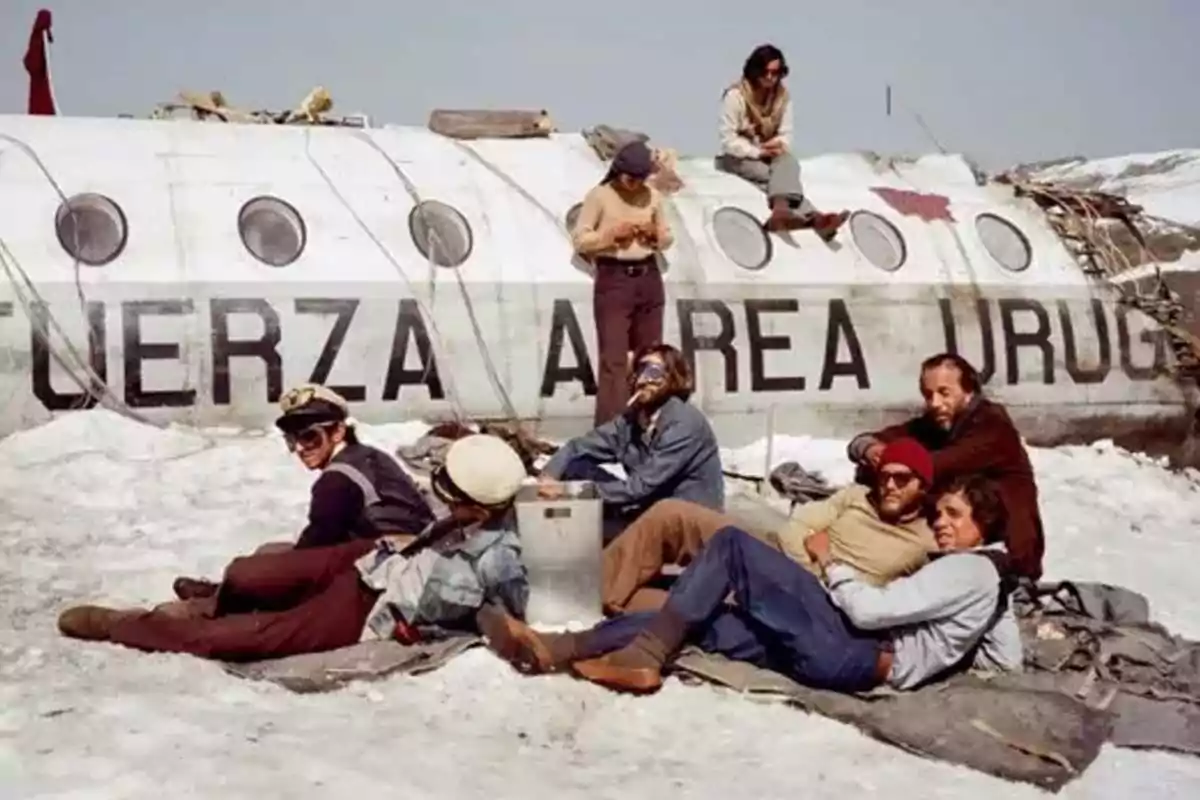 A group of people rests next to the remains of a plane in a snowy landscape. A group of people rests next to the remains of a plane in a snowy landscape.