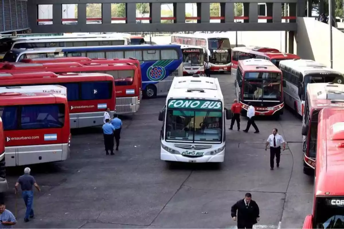 Una terminal de autobuses con varios vehículos estacionados y personas caminando alrededor.