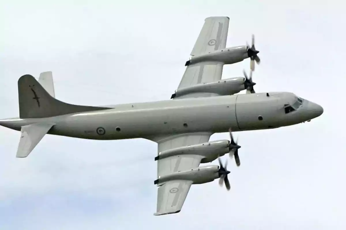 Avión militar de cuatro motores en vuelo.