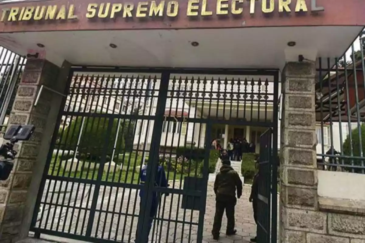 Entrada principal del Tribunal Supremo Electoral con una puerta de rejas y personas entrando al edificio.