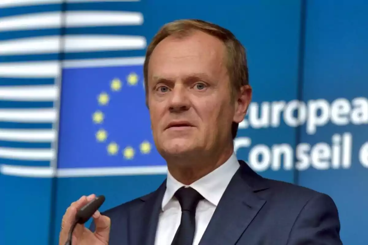 Un hombre en traje hablando frente a un fondo con el logotipo de la Unión Europea. Un hombre en traje hablando frente a un fondo con el logotipo de la Unión Europea.