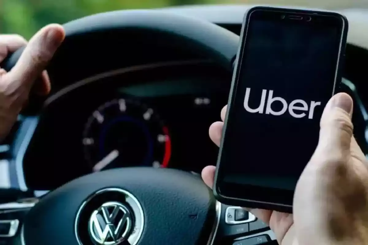 Person holding a phone with the Uber app open while driving a Volkswagen car