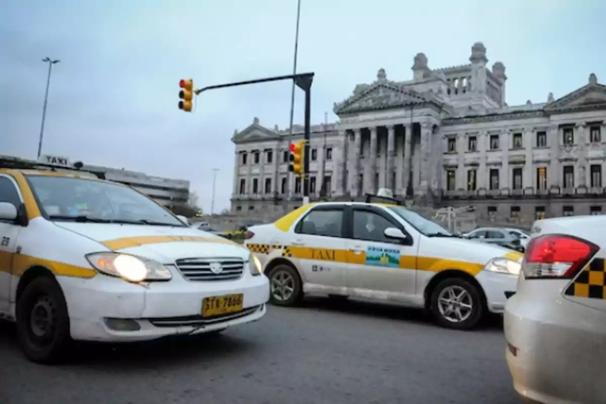 Taxis driving in front of a historic building with columns and classical architecture.