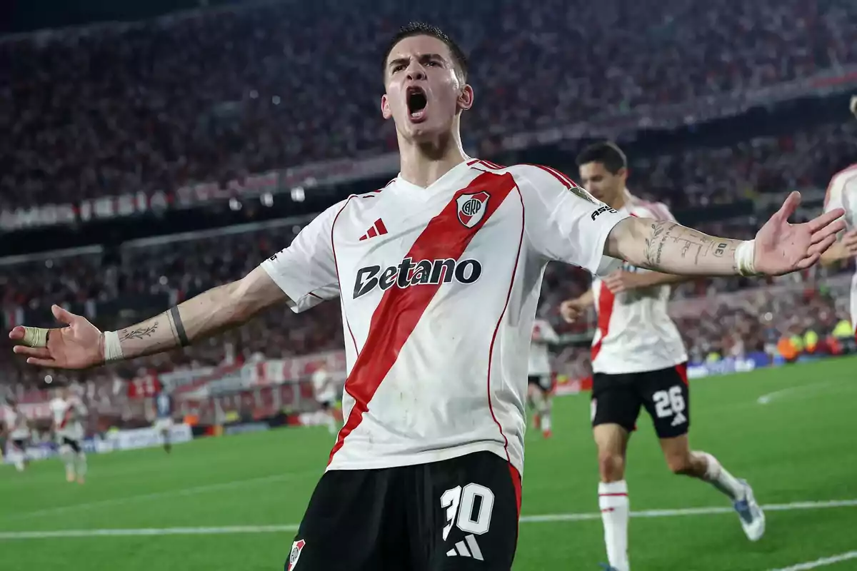 River Plate player celebrating a goal with arms outstretched in a stadium full of fans River Plate player celebrating a goal with arms outstretched in a stadium full of fans