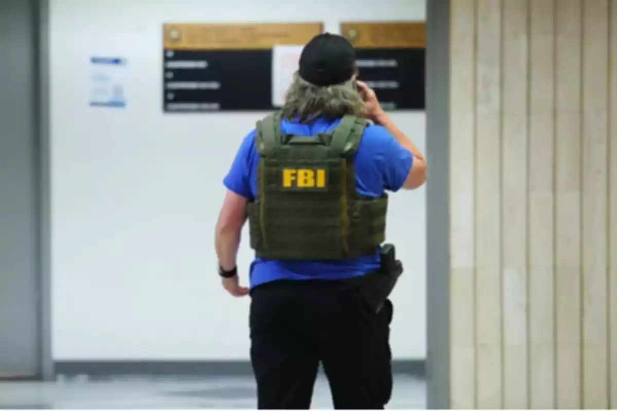 FBI agent seen from behind wearing a bulletproof vest and talking on the phone inside a building FBI agent seen from behind wearing a bulletproof vest and talking on the phone inside a building
