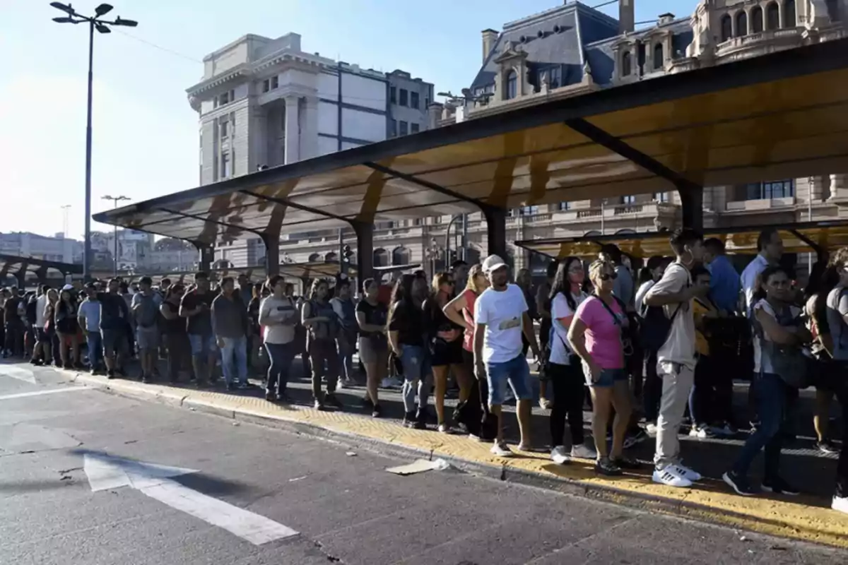 Personas haciendo fila en una estación de transporte público en un día soleado. Personas haciendo fila en una estación de transporte público en un día soleado.