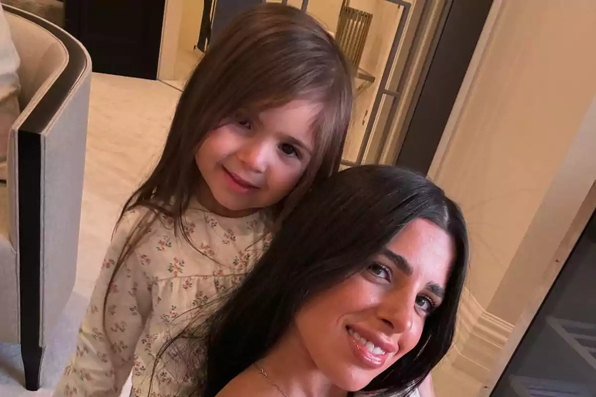 A woman and a girl smile together in a stylish interior.