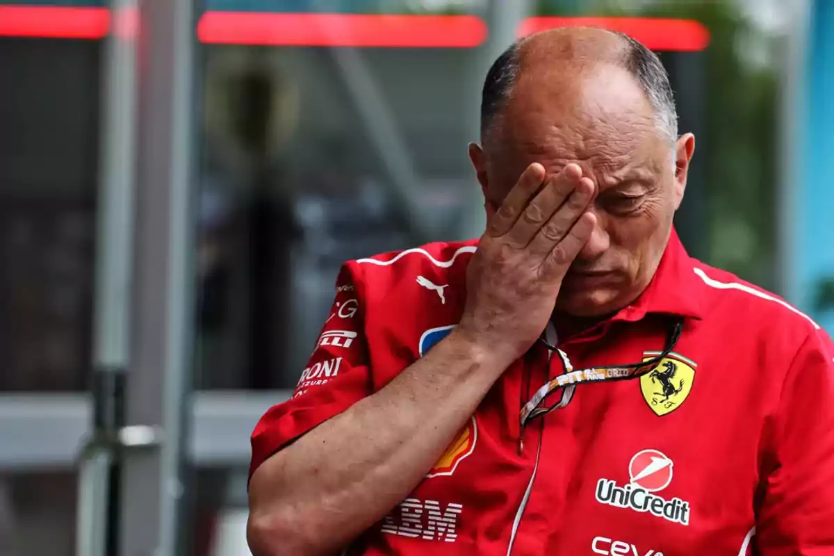 Man in a red Ferrari uniform covering his face with one hand in a gesture of frustration Man in a red Ferrari uniform covering his face with one hand in a gesture of frustration