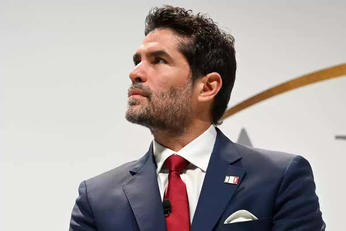 Hombre de cabello oscuro y barba con traje azul y corbata roja mirando hacia la izquierda Hombre de cabello oscuro y barba con traje azul y corbata roja mirando hacia la izquierda