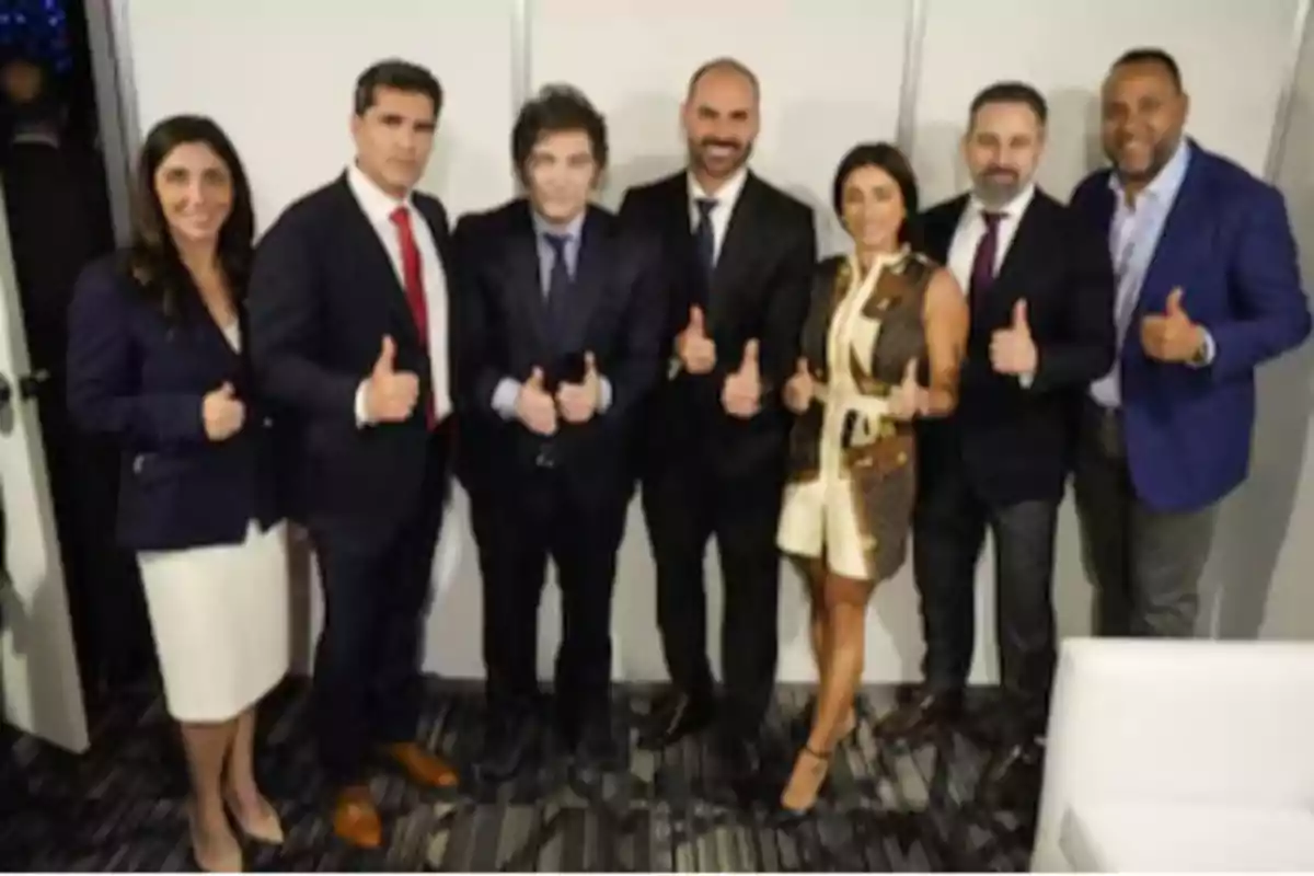 Un grupo de personas posando juntas, todas con trajes formales y levantando el pulgar en señal de aprobación.