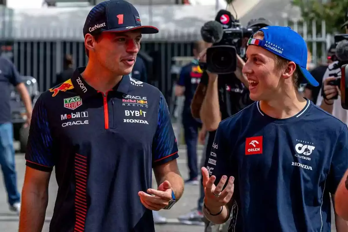 Max Verstappen y Lawson del equipo Red Bull de Fórmula 1 conversan mientras caminan, rodeados de cámaras y equipo de grabación. Max Verstappen y Lawson del equipo Red Bull de Fórmula 1 conversan mientras caminan, rodeados de cámaras y equipo de grabación.