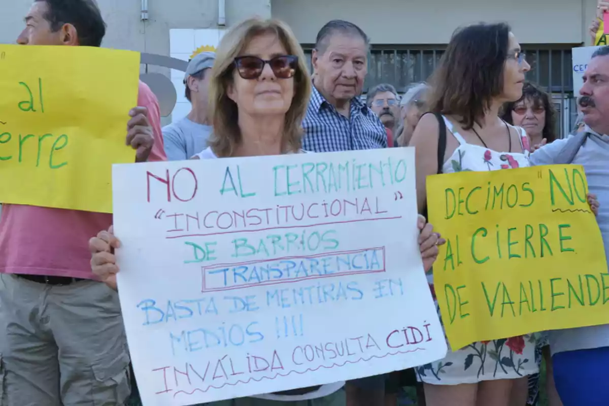 Personas sosteniendo carteles de protesta contra el cierre de barrios.