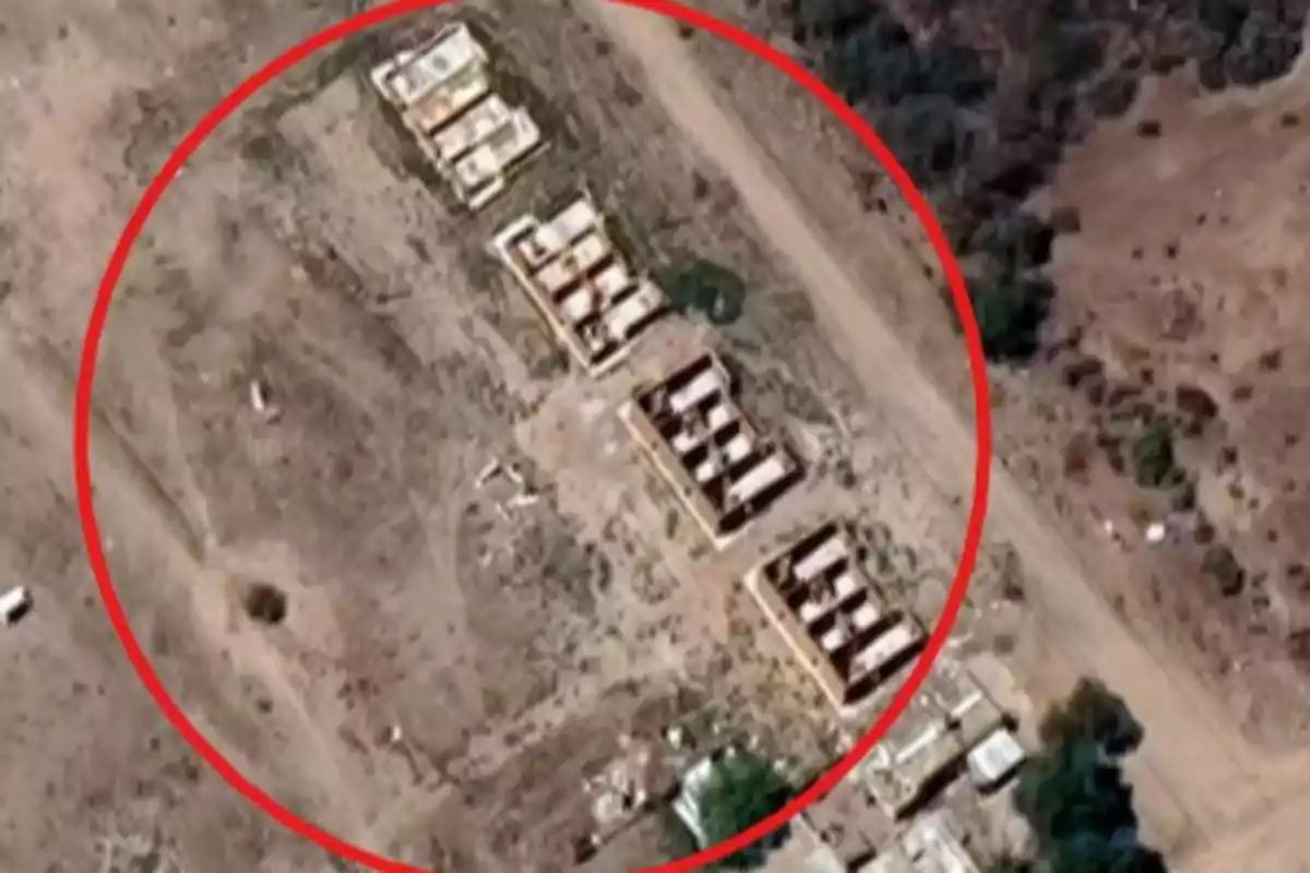 Aerial view of several abandoned and deteriorated structures on arid land, surrounded by a red circle