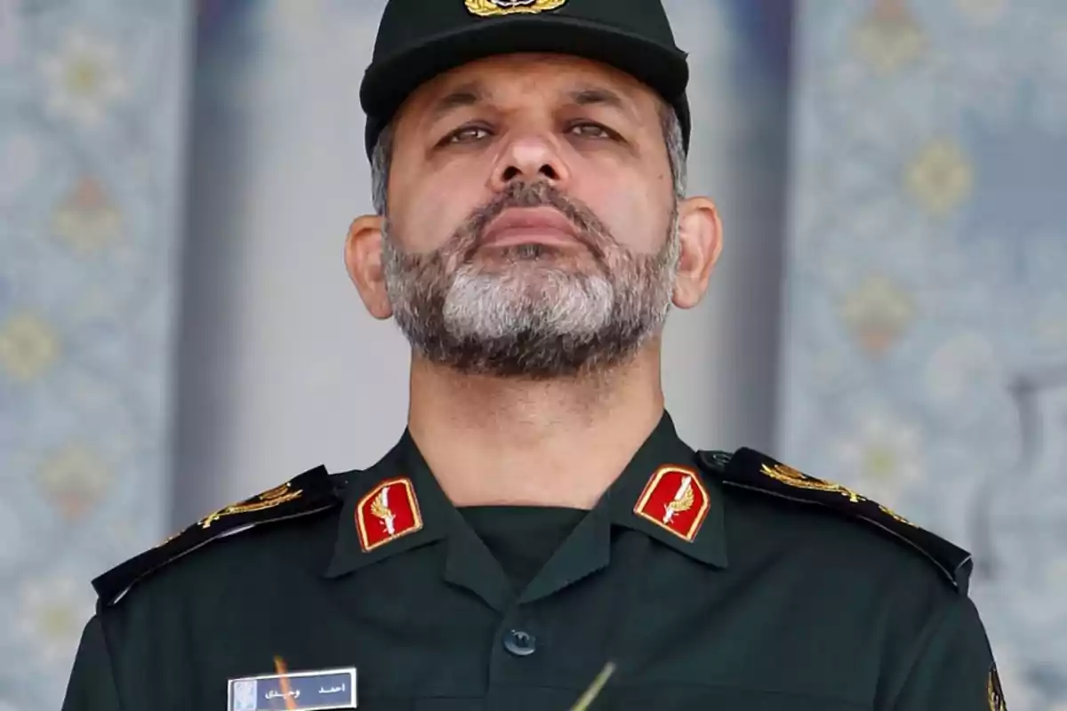 Man with a beard and dark green military uniform looking straight ahead Man with a beard and dark green military uniform looking straight ahead