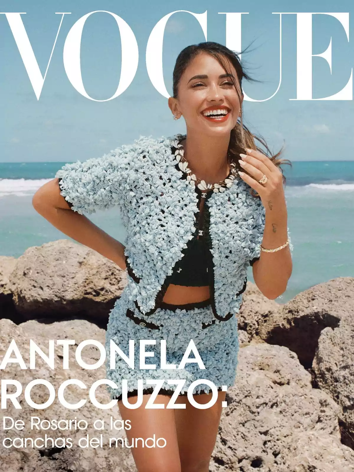 Vogue magazine cover with a woman smiling on the beach, wearing a light blue outfit. Vogue magazine cover with a woman smiling on the beach, wearing a light blue outfit.