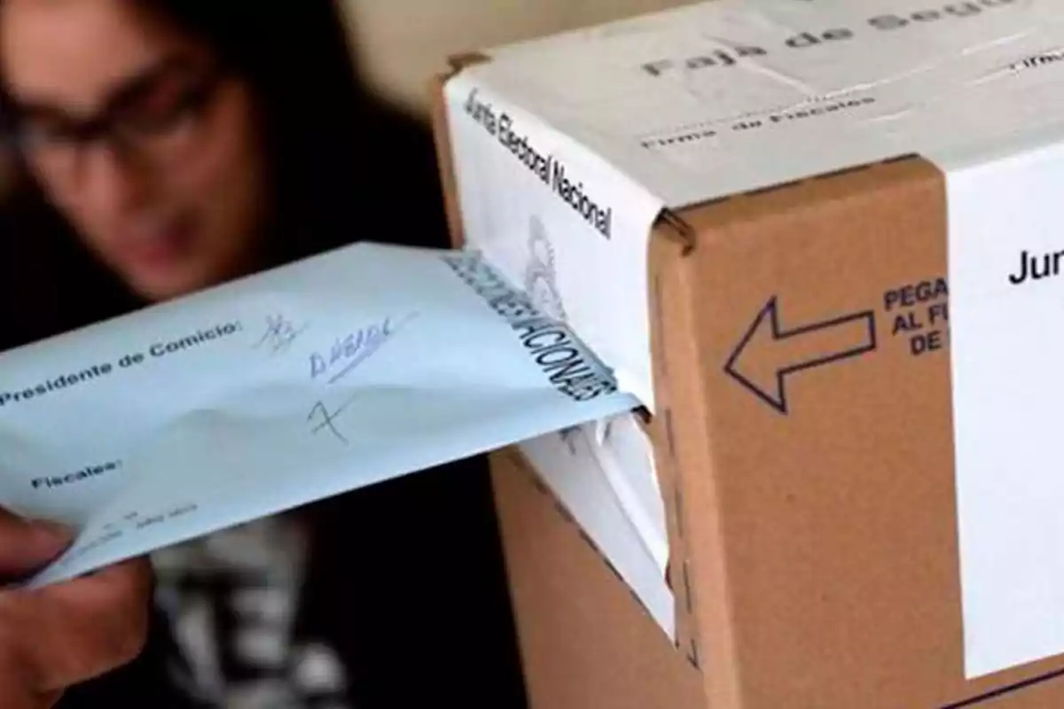 Persona introduciendo un sobre en una urna electoral durante una votación. Persona introduciendo un sobre en una urna electoral durante una votación.