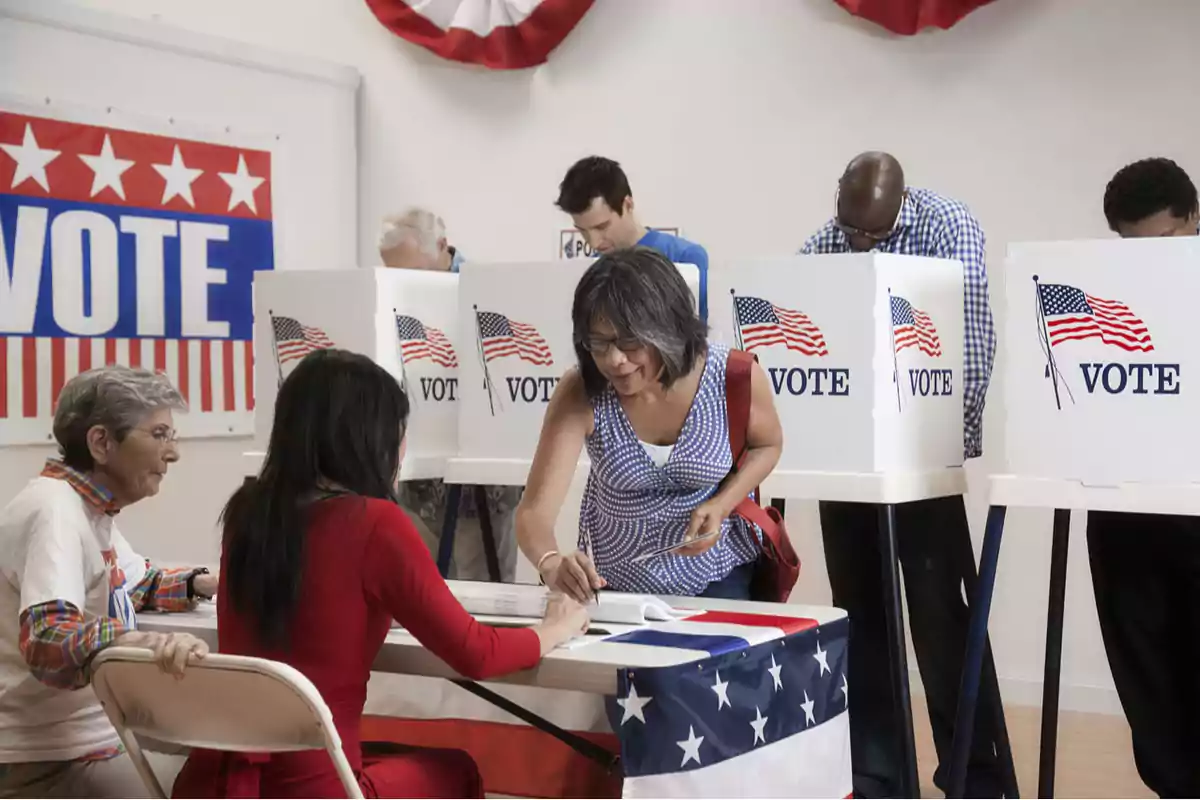 People participating in the voting process at a polling station with booths and patriotic decorations.
