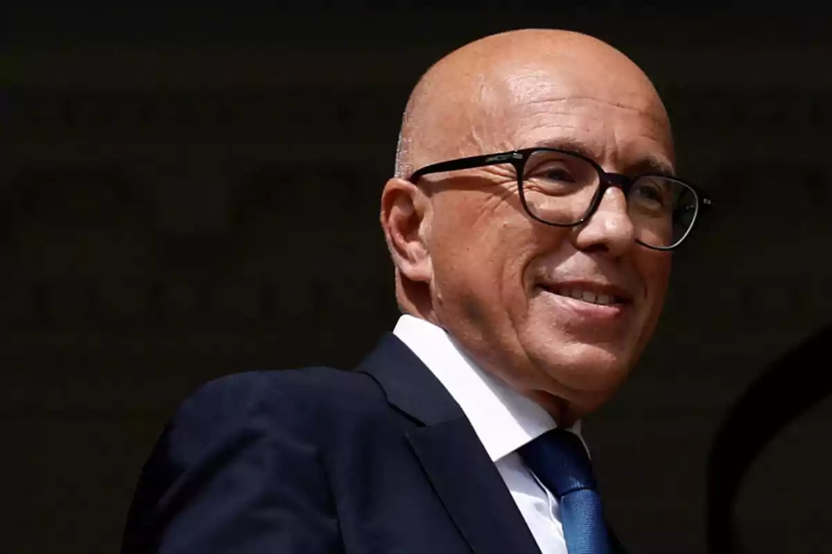 Hombre calvo con gafas y traje azul sonriendo Hombre calvo con gafas y traje azul sonriendo