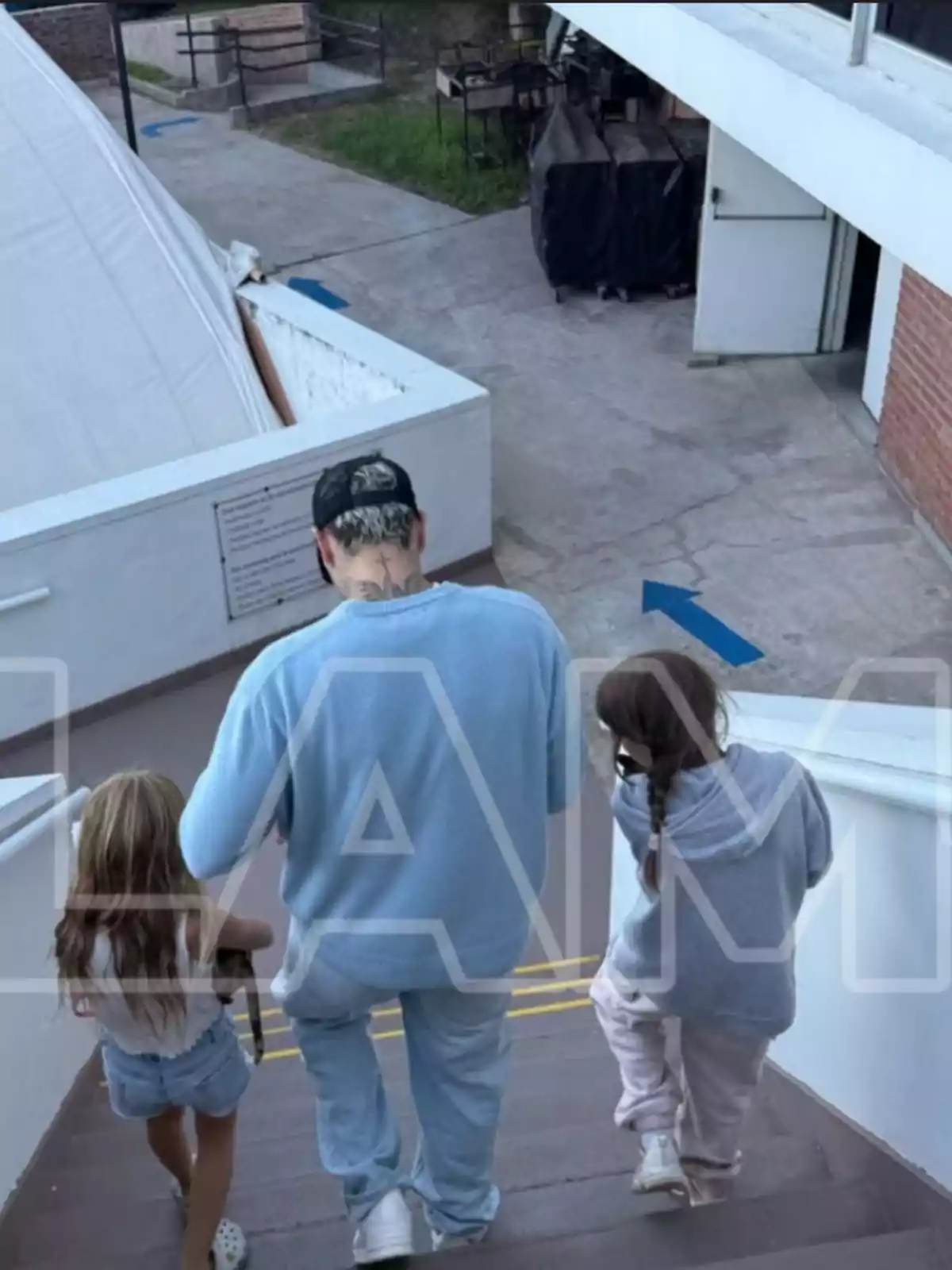 Un hombre con gorra y dos niñas bajan unas escaleras al aire libre. Un hombre con gorra y dos niñas bajan unas escaleras al aire libre.