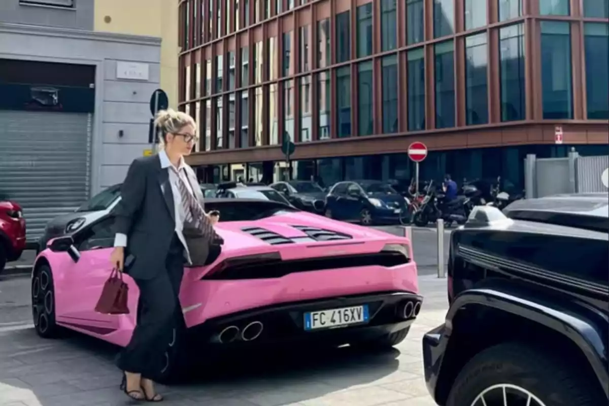 Woman with glasses and a gray suit walking next to a pink sports car parked on an urban street Woman with glasses and a gray suit walking next to a pink sports car parked on an urban street