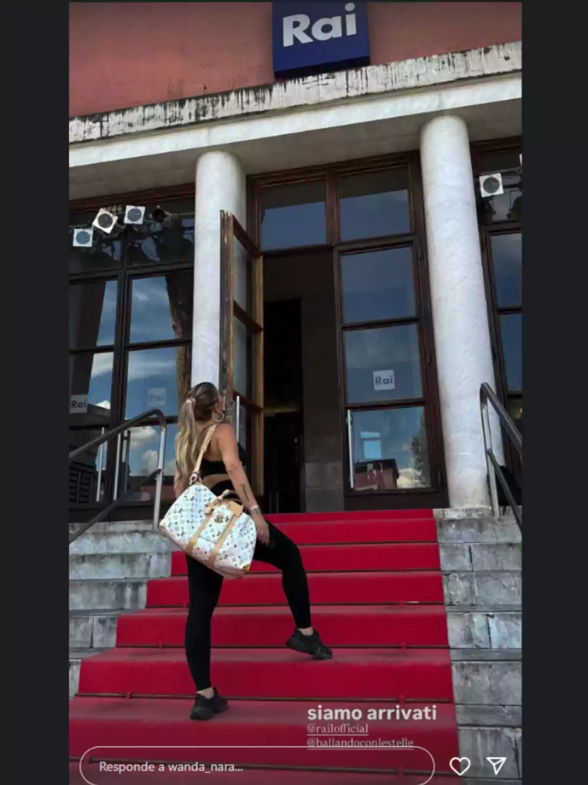 Woman with a large bag going up red stairs toward the entrance of a building with a Rai sign Woman with a large bag going up red stairs toward the entrance of a building with a Rai sign