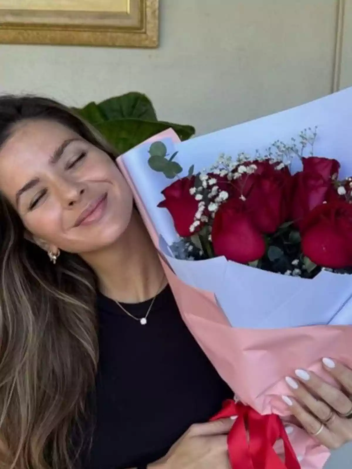 A person smiles while holding a bouquet of red roses wrapped in paper. A person smiles while holding a bouquet of red roses wrapped in paper.