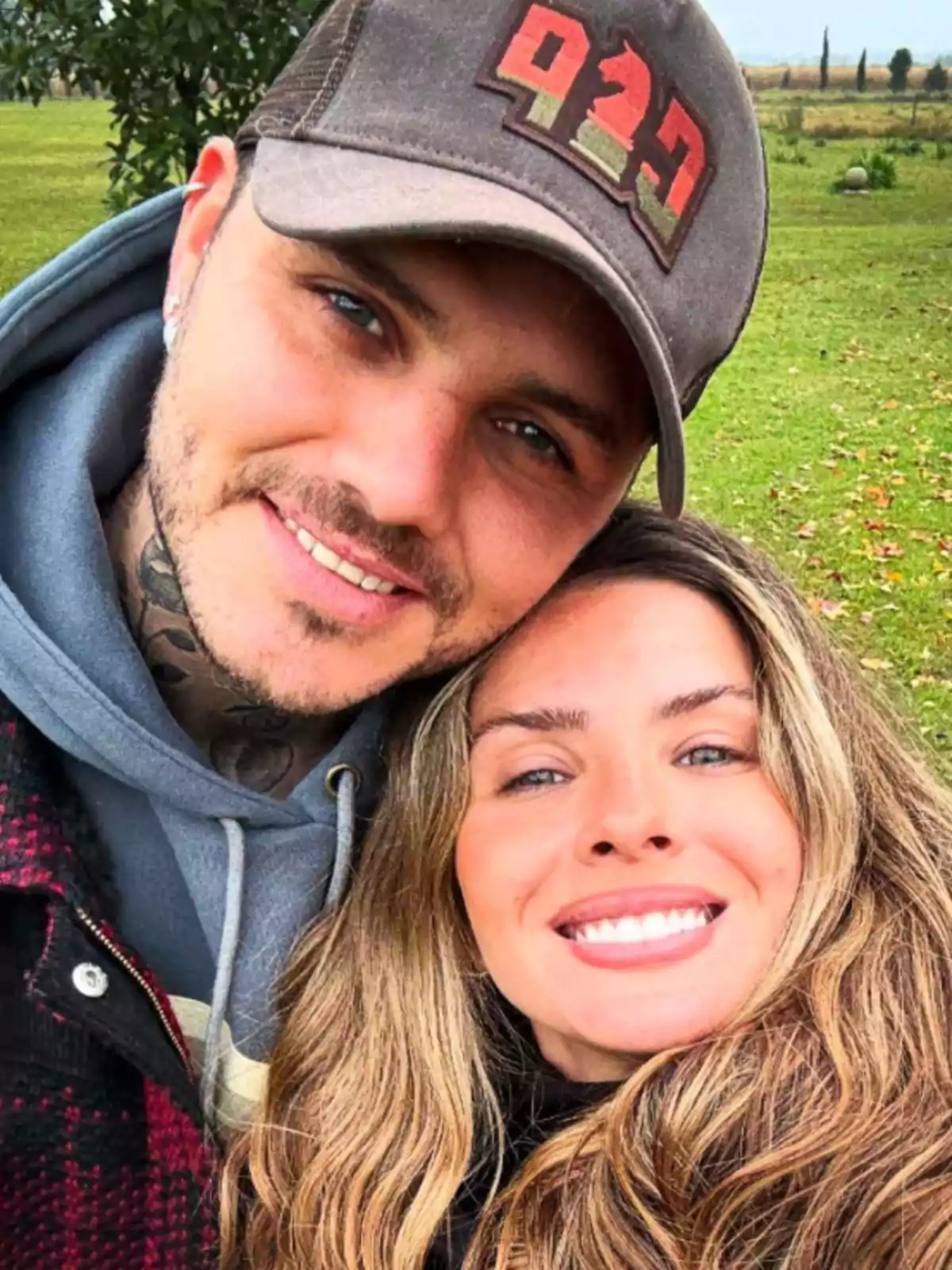 Pareja joven sonriendo al aire libre con césped y árboles de fondo Pareja joven sonriendo al aire libre con césped y árboles de fondo